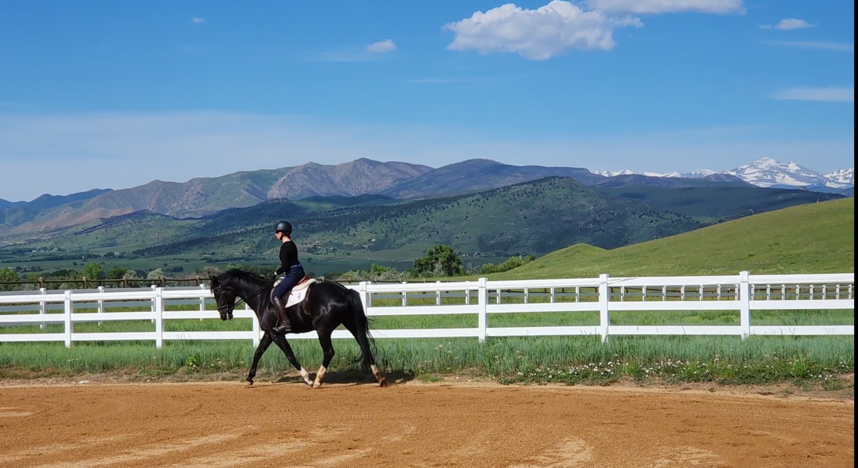Rider working a horse in the outdoor arena with beautiful mountain views at Lone Tree Acres